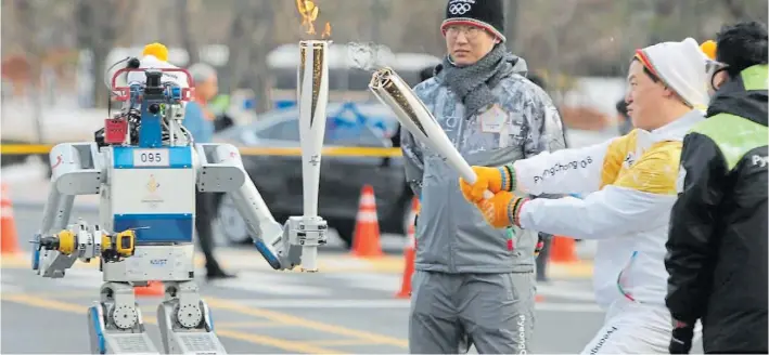  ??  ?? Antorcha. Un robot lleva el fuego que servirá para darle inicio y final a las competenci­as en una imagen jamás vista en la historia de los Juegos. La ciudad ya vive una fiesta olímpica.