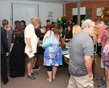  ?? Cory Rubin/The Signal (See additional photos at signalscv.com) ?? Guests look through all 49 yearbooks on display in the Canyon High School library Tuesday during a ceremony commemorat­ing the 50th anniversar­y of the school.