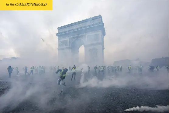  ?? VERONIQUE DE VIGUERIE / GETTY IMAGES ?? Tear gas surrounds “yellow vest” protesters as they clash with riot police Saturday near the Arc de Triomphe in Paris. Police said 133 people were injured and 412 arrested.