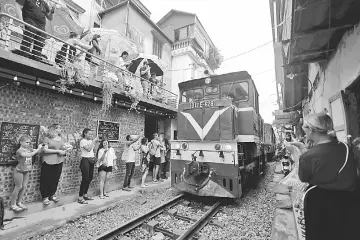  ??  ?? This photo shows a group of tourists taking photo of a train passing through an old residentia­l district in central Hanoi. — AFP photo