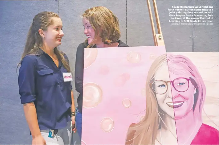  ?? GABRIELA CAMPOS/NEW MEXICAN FILE PHOTO ?? Students Hannah Weybright and Faith Pennell-Sutton stand next to a joint painting they worked on with their Inspire Santa Fe mentor, Pete Jackson, at the annual Festival of Learning at SITE Santa Fe last year.