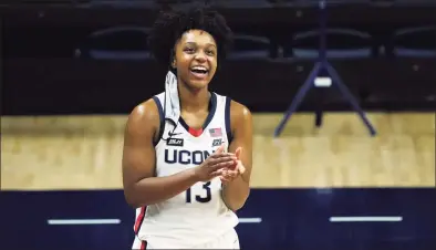  ?? David Butler II / Associated Press ?? UConn’s Christyn Williams (13) reacts to the stadium display as family and friends congratula­te her on her 1,000th point after beating DePaul last month.