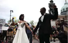  ?? Tyger Williams, The Philadelph­ia Inquirer ?? Kerry Anne Perkins and Michael Gordon realized amid the pandemic they would have to cancel their wedding but wound up having a microweddi­ng on June 6. As they did their first look, a massive Black Lives Matter demonstrat­ion arrived at Philadelph­ia’s Logan Square. Photos of the couple holding hands, fists raised, with thousands of people surroundin­g them went viral.