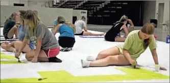  ?? Jeremy stewart ?? Rockmart High School cheerleade­rs work on a banner for the school’s football team to run through at their scrimmage against Bremen on July 29.