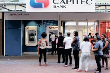  ?? | REUTERS ?? CUSTOMERS queue to withdraw money from an ATM outside a Capitec branch in this file picture.