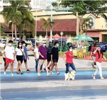  ?? PHILIPPINE STAR/ MIGUEL DE GUZMAN ?? PEOPLE cross Roxas Boulevard in Manila, May 1.