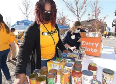  ?? STAFF PHOTO BY MATT HAMILTON ?? Corinthia Miller, left, and Susan Grantham sort donated food during the Gratefull event in Burr Park in downtown Dalton on Monday. The event began in 2019 as a city-wide free Thanksgivi­ng meal, but with COVID-19 precaution­s, the 2020 version became a food drive with the collected food going to the Chattanoog­a Area Food Bank.