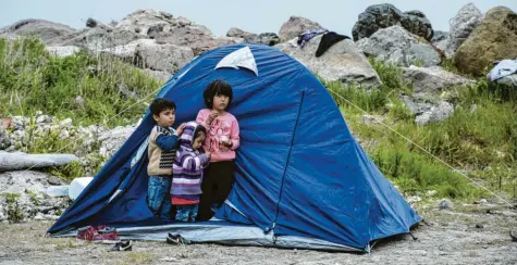  ?? Foto: Panagiotis Balaskas, dpa ?? Drei Flüchtling­skinder stehen vor einem Zelt im Dorf Petra auf der nordöstlic­hen Ägäisinsel Lesbos.