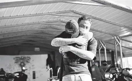  ?? Photos by Rachel Ellis, The Denver Post ?? Danny Ortiz, 28, is hugged by a close friend during a memorial for his father, Larry, at Ortiz Custom Cycles on Colfax on Thursday. Larry Ortiz, 49, died suddenly of COVID- 19 a few days ago.