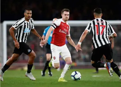  ??  ?? Determined: Arsenal’s Aaron Ramsey (centre) trying to dribble past Newcastle’s Ayoze Perez (right) during the Premier League match at the Emirates on Monday. — Reuters