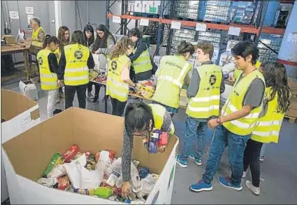  ?? JORDI ROVIRALTA ?? Voluntario­s del Banc d’Aliments ayer en la sede de la Zona Franca