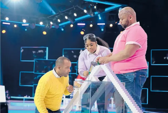  ?? RAY MICKSHAW/FOX ?? DeMond Nason, right, huddles with teammates Michael Carrasquil­lo and Breenae Washington during the competitio­n series “Domino Masters.” “Part of (domino) art is the fall, that’s what I love about it,” Nason said.