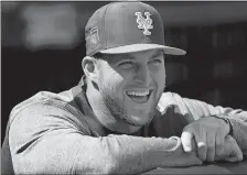  ?? JOHN BAZEMORE/AP PHOTO ?? Tim Tebow of the Mets laughs with teammates in the dugout before a spring training game against the Yankees on March 7 at Port St. Lucie.