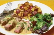  ?? LINDA GASSENHEIM­ER/ TNS ?? Brandy flambéed steak with garlic potatoes.