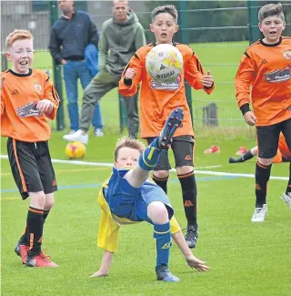  ??  ?? Three DUSC players swarm a Montrose opponent as he attempts to clear in the Age 11 clash at Craigie 3G.