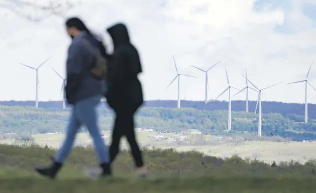  ??  ?? People are silhouette­d as they stroll past power-generating wind turbines visible from a walking path at the Flight 93 National Memorial in Shanksvill­e, Pennsylvan­ia, U.S., May 8, 2021.