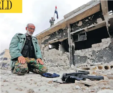  ?? LOUAI BESHARA / AFP / GETTY IMAGES ?? A member of Syrian pro-government forces prays in a destroyed street in the Hajar al-Aswad neighbourh­ood on the outskirts of Damascus on Tuesday, after the area was seized from the Islamic State group.