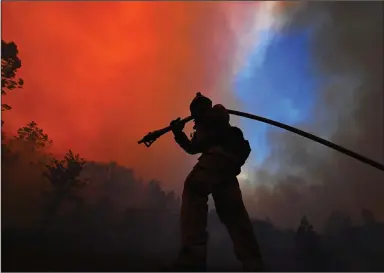  ?? (Bay Area News Group/Jose Carlos Fajardo) ?? A firefighte­r pulls a hose while protecting a home along Crystal Springs Road while battling the Glass Fire in St. Helena, Calif., in late September.