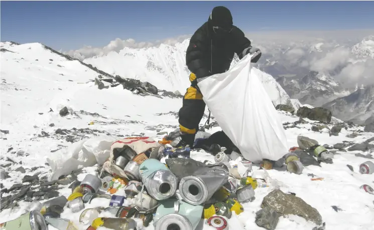  ?? NAMGYAL SHERPA / AFP / GETTY IMAGES ?? A Nepalese Sherpa collects garbage on Mount Everest. Local waste management group Sagarmatha Pollution Control Committee has had several campaigns and programs to clean up the mountain since the 1990s, when commercial climbing began to take off on the world’s tallest peak — and a long-festering littering problem began.