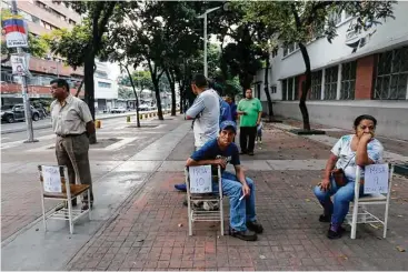  ?? Ariana Cubillos / Associated Press ?? A few voters wait outside a polling station Sunday in Caracas, Venezuela, to cast ballots for a constituti­onal assembly. Most stayed away after government foes said the election could be used to impose unlimited powers.