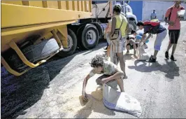  ?? ARIANA CUBILLOS / ASSOCIATED PRESS 2016 ?? A youth uses his pillow as a bag to collect rice that shook loose from a food cargo truck and landed on the pavement near the port in Puerto Cabello, Venezuela. The port handles the majority of Venezuela’s food imports.