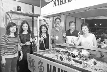  ??  ?? Lau (third right), Tiong (right) and others at one of the 300 stalls at the food fair.
