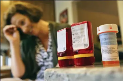  ?? THE ASSOCIATED PRESS ?? Shelley Ewalt sits in her home, in Princeton, N.J., near an amber-colored CVS pharmacy prescripti­on bottle, right, and two uniquely designed red ones from Target. After CVS took over operation of Target’s drugstores earlier this year, distraught...