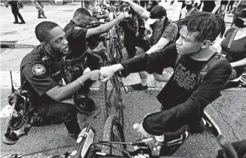  ?? CURTIS COMPTON/ATLANTA JOURNAL-CONSTITUTI­ON ?? Atlanta police Officer J. Coleman and protester Elijah Raffington bump fists Wednesday outside the CNN Center at Olympic Park.