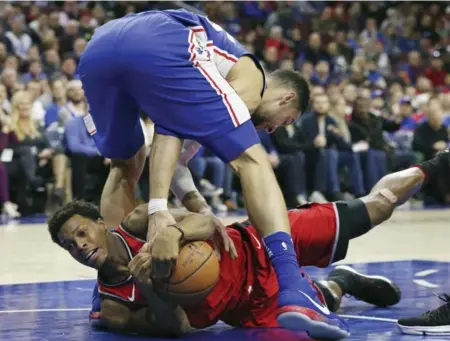  ?? RICH SCHULTZ/THE ASSOCIATED PRESS ?? Raptors guard Kyle Lowry, bottom, battles for a loose ball with Philadelph­ia counterpar­t Ben Simmons in the third quarter of Monday’s loss at the Wells Fargo Center. Lowry, returning from a bruised tailbone that kept him out of three games, went...