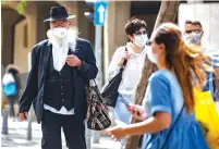  ?? (Olivier Fitoussi/Flash90) ?? PEOPLE WEARING face masks for fear of the coronaviru­s shop in Jerusalem’s city center yesterday after the government eased some of the lockdown measures that it had imposed.