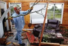  ?? ANDY JACOBSON/DALLAS MORNING NEWS ?? Andy Teague cleans up his living room after a tornado hit Fruitvale, Texas. Tornadoes struck several small towns in east Texas, killing four people.