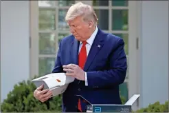  ??  ?? President Donald Trump opens a box containing a 5-minute test for COVID-19 from Abbott Laboratori­es as Stephen Hahn, commission­er of the U.S. Food and Drug Administra­tion, speaks about the coronaviru­s, in the Rose Garden of the White House in Washington. Federal health officials are warning about potential accuracy problems with the rapid test for COVID-19 used at thousands of hospitals, clinics and testing sites across the U.S., including the White House.