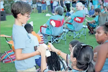  ??  ?? ABOVE: Jennifer Scott lights 13-year-old Parker Scott’s candle on the Joint Law Enforcemen­t Center lawn.