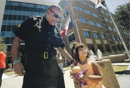  ?? Barbara Davidson Los Angeles Times ?? SGT. LEROY QUIGG greets a girl at the Dallas police headquarte­rs, where visitors pay respects to the five officers who were fatally shot.