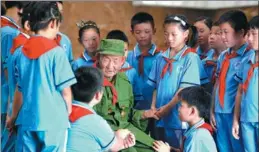  ?? MU YU / XINHUA ?? Above: Students from a primary school in Nangong city, Hebei province, listen to Sun Yunbao, a veteran, at a local public cemetery honoring war martyrs.