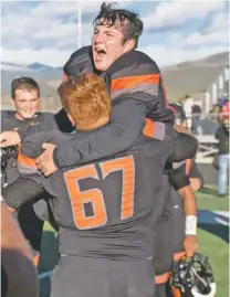  ??  ?? Taos’ Santiago Salazar, held by Dominic Lopez, celebrates Saturday after the Tigers secured the Class 4A championsh­ip.