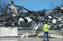  ?? ELIJAH NOUVELAGE / REUTERS ?? A man looks at a damaged Bombardier Challenger 350 jet after a string of tornadoes in Eufaula, Alabama, on Tuesday.