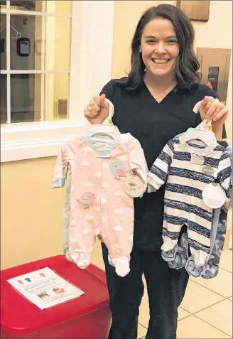  ??  ?? Alyssa Pinsent holds up recent donations of newborn sleepers at Andrews of Charlottet­own where she is accepting donations. She will be donating the sleepers to the Queens Elizabeth Hospital.