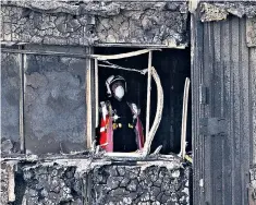  ??  ?? A firefighte­r surveys the scene from inside the burnt-out tower block