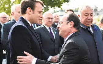  ?? Stephane De Sakutin / AFP / Getty Images ?? President-elect Emmanuel Macron (left) embraces outgoing President Francois Hollande at a Paris ceremony marking the 72nd anniversar­y of the victory over Germany in World War II.