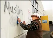  ?? AP PHOTO BY RICH PEDRONCELL­I ?? In this Feb. 1, file photo, Tom Garing cleans up racist graffiti painted on the side of a mosque in what officials are calling an apparent hate crime in Roseville.