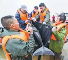  ?? FU JIANBIN / FOR CHINA DAILY ?? Local protection workers transport a finless porpoise from a temporary feeding place at a dock of Poyang Lake in Duchang, Jiangxi province, in March.