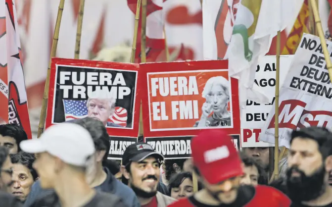  ??  ?? Protesters with signs bearing the faces of President Donald Trump and IMF Managing Director Christine Lagarde march against the G20 summit being held in Buenos Aires, Argentina, Nov. 30.