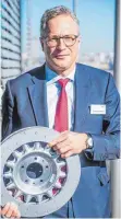  ?? FOTO: DPA ?? SHW-Chef Frank Boshoff mit einer Verbundbre­msscheibe für Peugeot: Die hochwertig­en Bremsschei­ben fertigt SHW in Neuhausen.