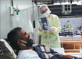  ?? AMANDA PEROBELLI / REUTERS ?? Fabiano Santana de Souza, 37, a patient suffering from the coronaviru­s, talks to his wife and daughter by a video call at a field hospital set up in a gym in Santo Andre, Brazil, on Wednesday.