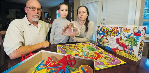  ?? ARLEN REDEKOP/PNG ?? Mitch, Angus and Paula Selman of Pitt Meadows with the syringe they found inside a Mouse Trap game. They said when they phoned the store, staff did not seem overly concerned but did pitch them on a sale for children’s clothing.