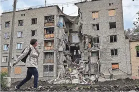  ?? ARIS MESSINIS/AFP VIA GETTY IMAGES ?? A woman walks by a destroyed apartment building in Bakhmut in the eastern Ukranian region of Donbass on Sunday.