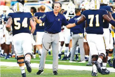  ?? STAFF PHOTO BY ROBIN RUDD ?? UTC football coach Rusty Wright congratula­tes offensive linemen after the Mocs kicked an extra point during Thursday night’s season opener against Austin Peay. The Governors scored the final 14 points of the game to win 30-20.