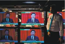  ?? Anthony Wallace / AFP/Getty Images ?? An employee at a Hong Kong electronic­s store looks at President Xi Jinping speaking to Communist Party Congress.