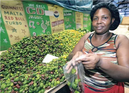  ?? GLADSTONE TAYLOR PHOTOS ?? Christine Bantin packages Scotch bonnet peppers at her stall in Coronation Market.